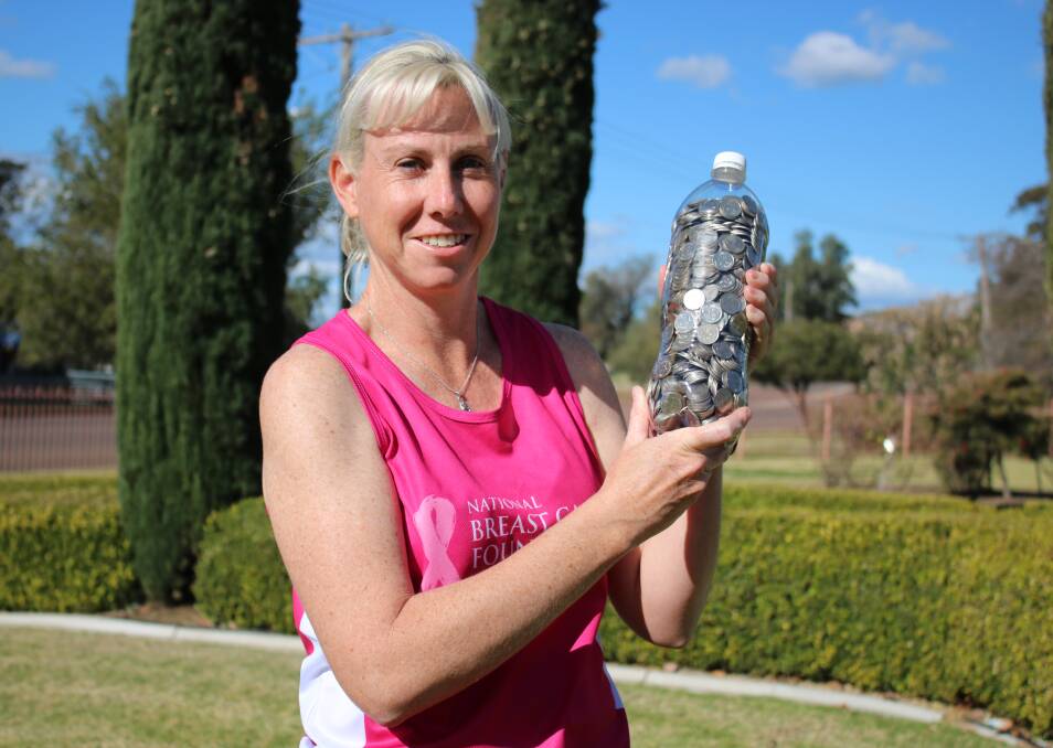 Gunnedah woman Casey Hatch with a bottle of five cent pieces collected by residents and visitors. The coins are part of her fundraising activities for the National Breast Cancer Foundation.