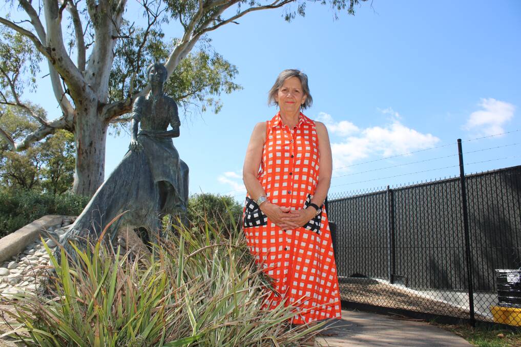 TOO CLOSE: Dorothea Mackellar Memorial Society member Philippa Murray stands between the statue and the fence of the Gunnedah Memorial Pool Complex on South Street.