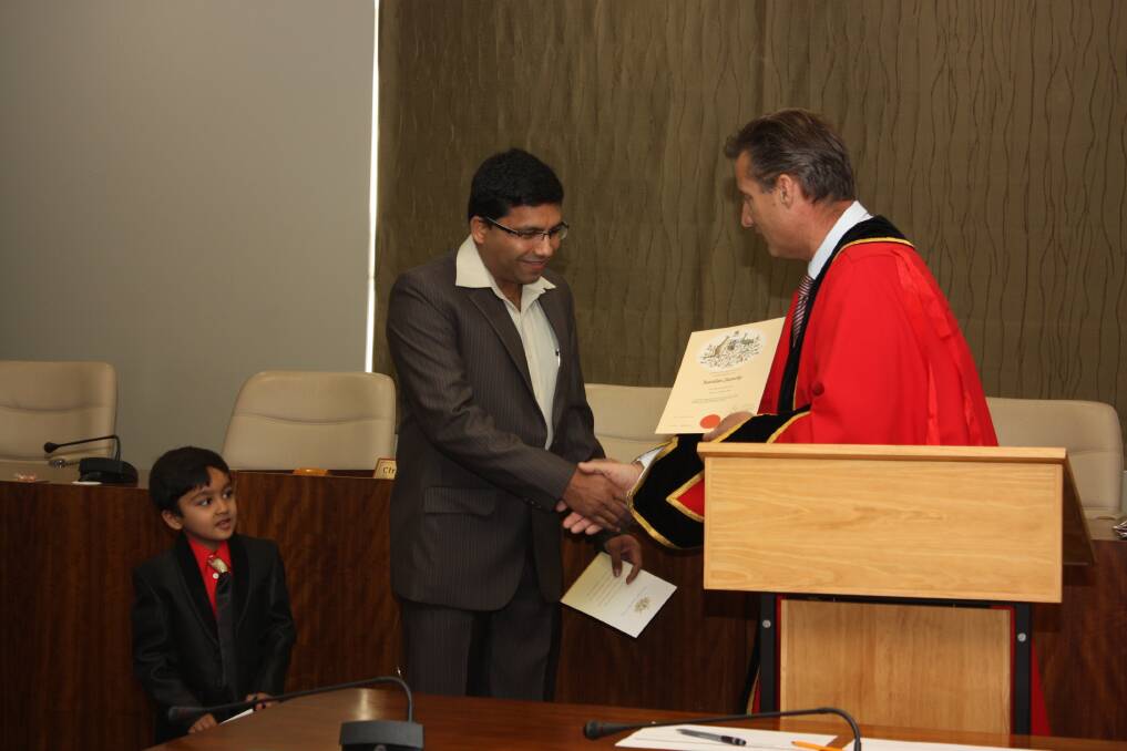 Muhammad Khan receives his citizenship certificate from Gunnedah mayor Jamie Chaffey as his son Abdul waits for his turn.