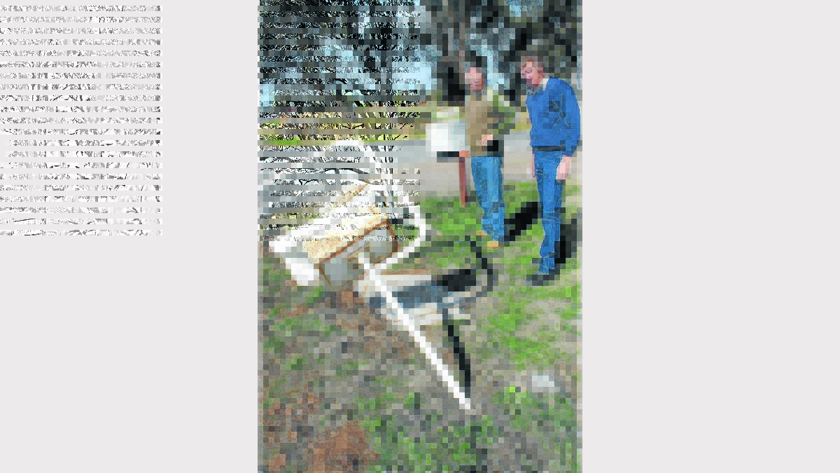 Ken Hill and Steve Wicks inspect the few mailboxes that are left after weekend vandals ripped Mr Wicks’ letterbox from the ground and dumped it in the river.