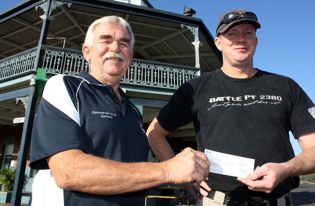 Peter Louis (left) from the Commercial Hotel, Curlewis, hands over a cheque for $3000 raised in support of ‘Sharing the Load’ stretcher carry challenge organised by Greg Sams (right). 