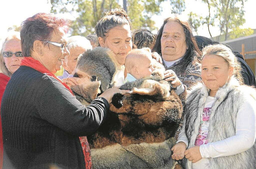 A TRADITIONAL naming ceremony involves the mother and child being wrapped in a possum skin by their aunties and grandmothers, to symbolise their responsibility for the child. Pictured, Jerrica Wortley (mother) and family.