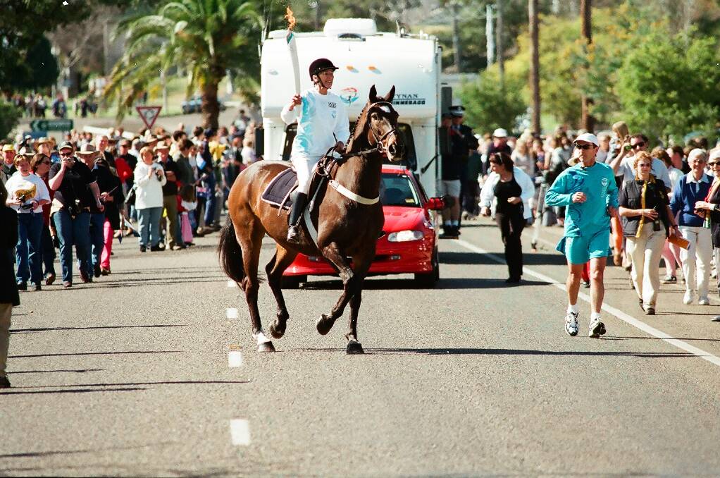 Bud Hyem riding Kibah Tic Toc through the streets of Gunnedah in 2000, carrying the Olympic torch.