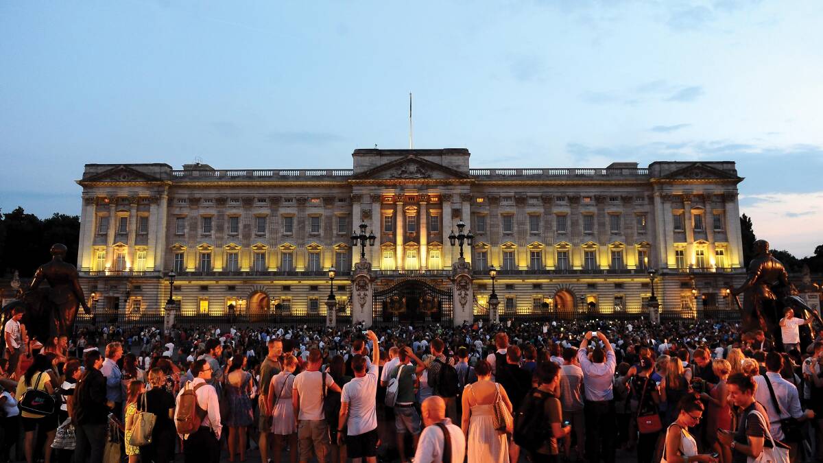 People gather outside a floodlit Buckingham Palace in London to mark the birth of a baby boy. Picture: Getty.
