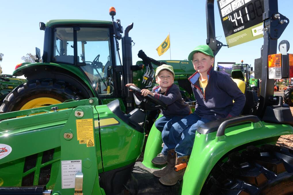 Peel Valley Machinery takes its AgQuip display "pretty seriously". Pictured are Crowley brothers Angus and Hugh from Barraba on a John Deere tractor at AgQuip last year.