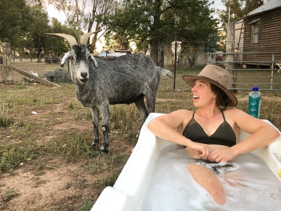 Sarah Sulman cooling off on a hot day in the outside bath. She is pictured with her pet goat Roger who she rescued from the abbatoirs.