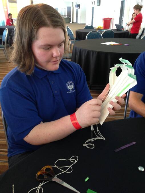 Shayne Williams at the prosthetic hand workshop using string on an engineered prosthetic hand.