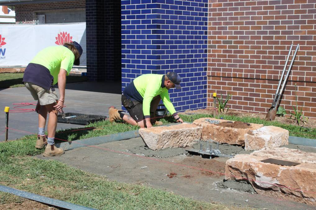GardenScape Design employees work on a feature out the front of the Gunnedah Police Station on Thursday. They are using sandstone blocks, which were the foundations of the original jail.