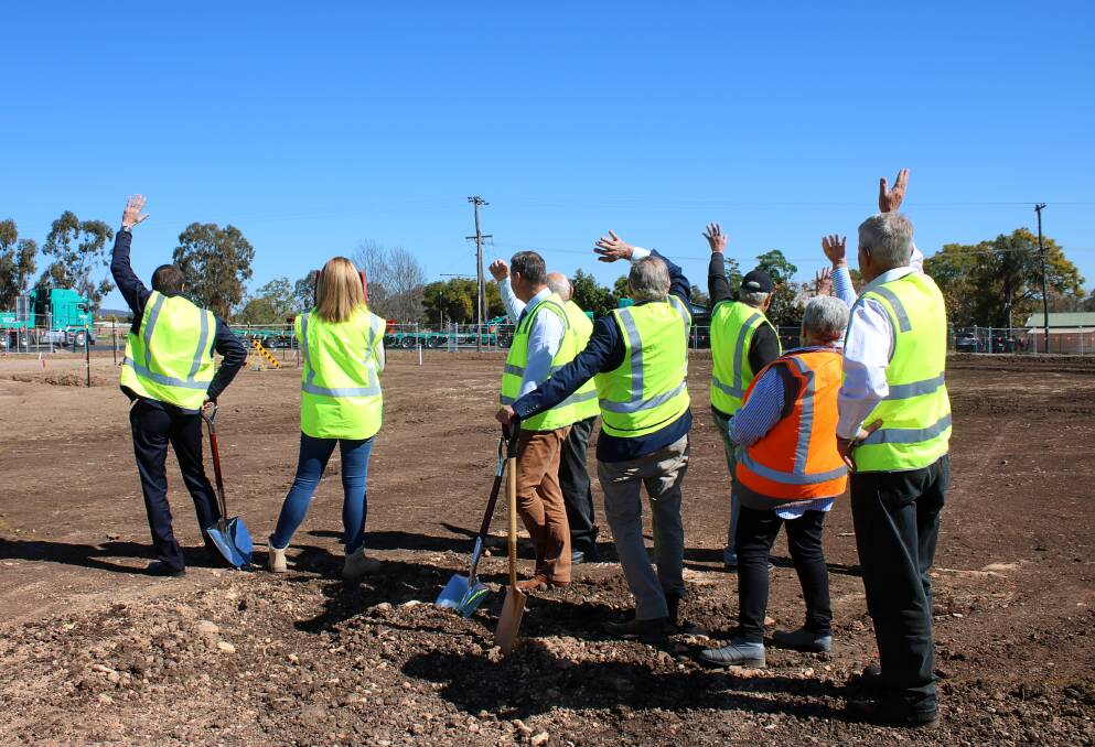 Gunnedah Shire Council staff on the site of the new roundabout wave at the driver of a heavy vehicle turning onto Boundary Road from the Oxley Highway on Friday.