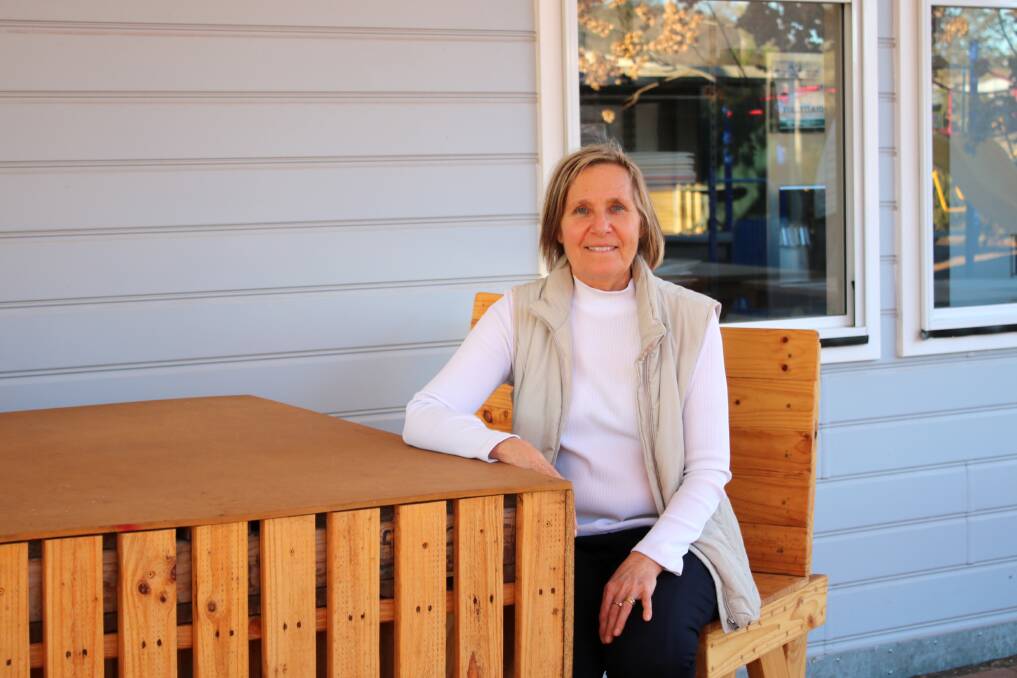 TurningPoint's Kim Gibson sitting in the outdoor area on furniture made in One of a Kind's Work for the Dole workshop.