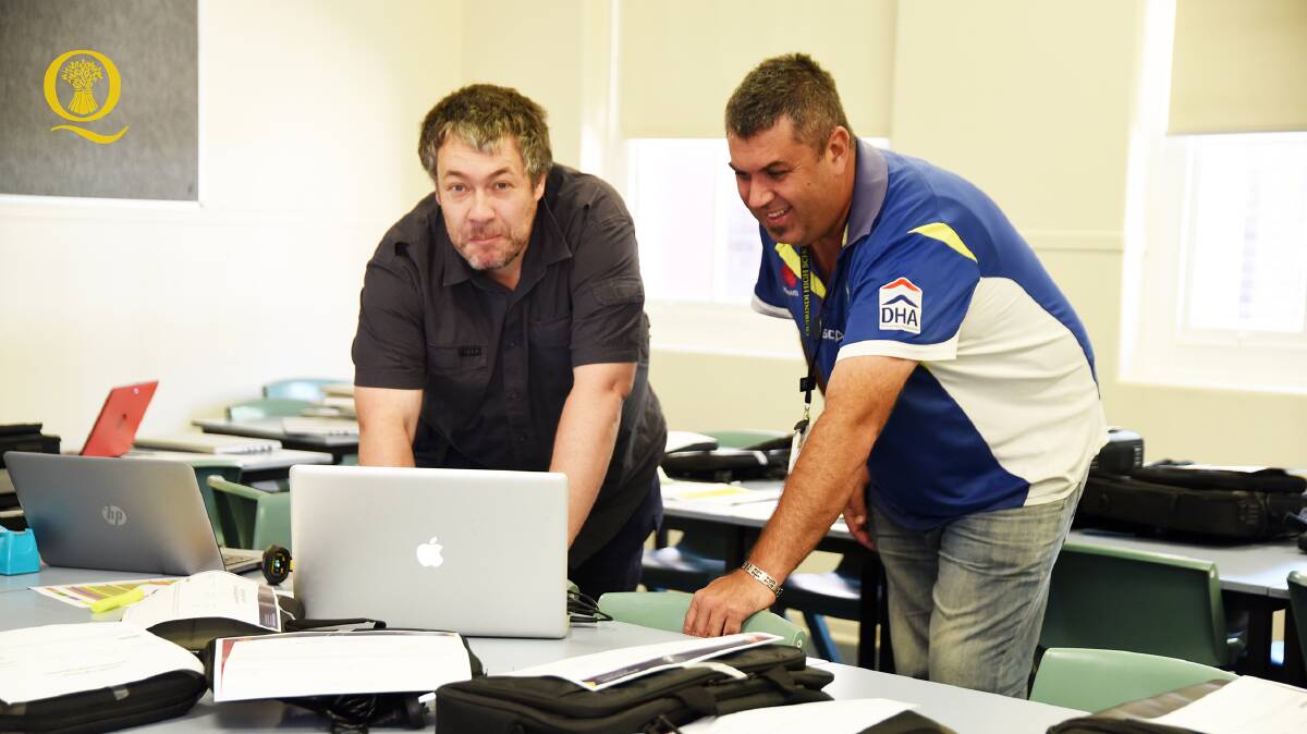 LAPPING IT UP: Mr Maczi and Mr Saunders from QHS setting up the laptops received thanks to Rural Aid. Photo: Contributed