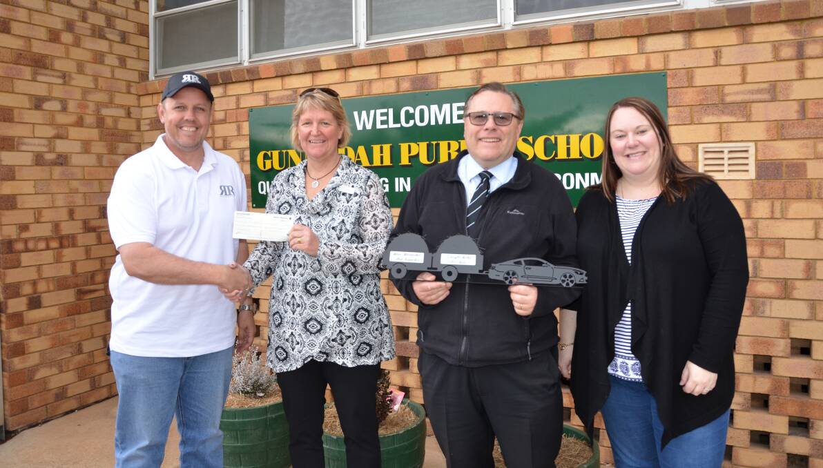HELPING HAND: Racing Revolution's Adam Drake and Angela Bartlett present Gunnedah Public School's Cathie McMaster and Gunnedah High School's Ken Whyte with a cheque for $3115. Photo: Billy Jupp 