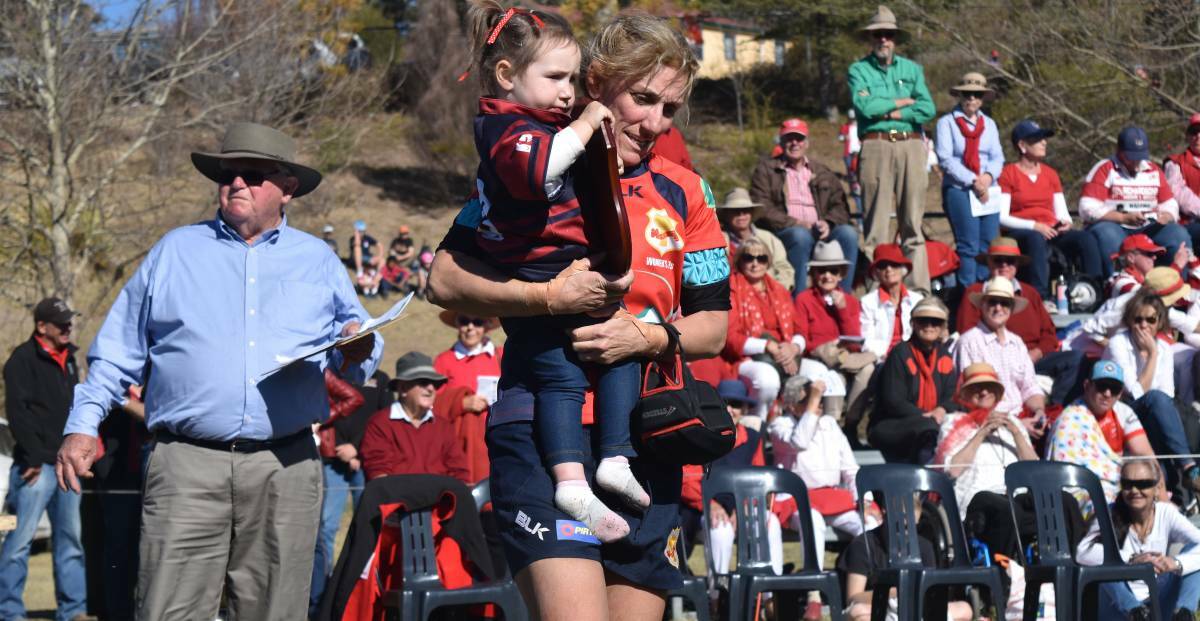 TEAK TOUGH: Nichole Carlyon carries Reggie, the two-year-old daughter of Gunnedah skipper Sarah Stewart, after the grand final despite breaking a rib in the match. "Yeah," Carlyon answered when asked if carrying Reggie hurt. Photo: Ben Jaffrey 