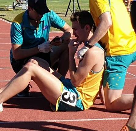OUCH: Gunnedah athlete Stuart Geddes receives medical attention after a heavy fall in the 3000-metre steeplechase at the Oceania Area Championships at Townsville.