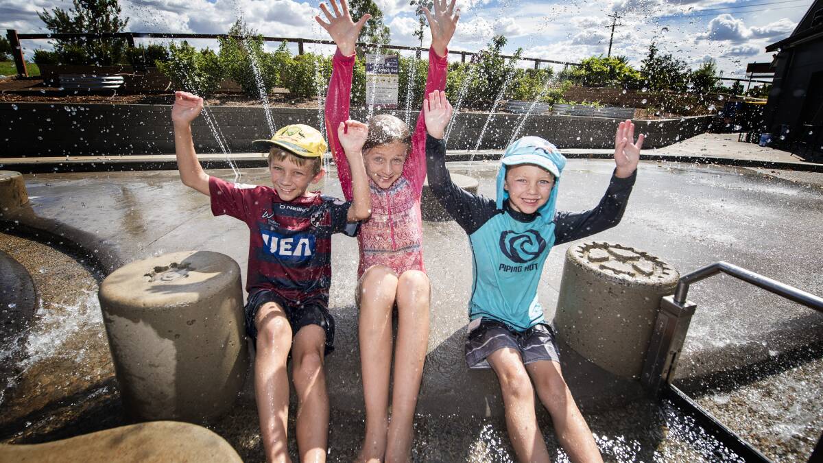 HOPE FOR RAIN: Aaron, Audrey and Allister Olsson enjoy some cool water at the park. Photo: Peter Hardin