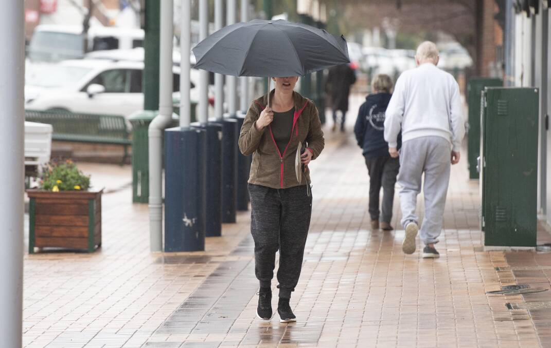 WET WEATHER: Local woman shelters from the rainy weather on July 27. Photo: Peter Hardin