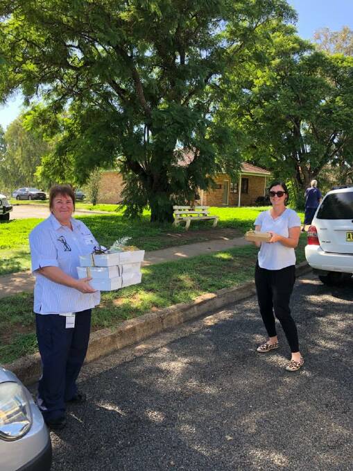 Gunnedah hospital maternity nurse unit manager Therese Mills receiving the package from PRAMS' Amber Donoghue, while adhering to social distancing rules. Photo: supplied
