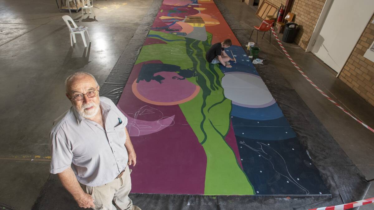 REPRESENTING GUNNEDAH: Mural project coordinator Dan Birkett in front of the work, with Toby Bartlett in the background painting stars into the night sky. Photo: Peter Hardin