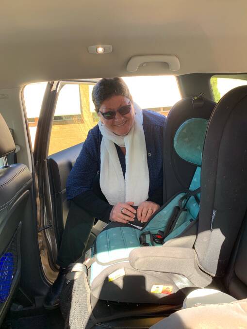 LPSC's Service NSW customer service officer Kay Brennan-Lee checking a child's car seat is properly restrained in a vehicle. Photo: supplied