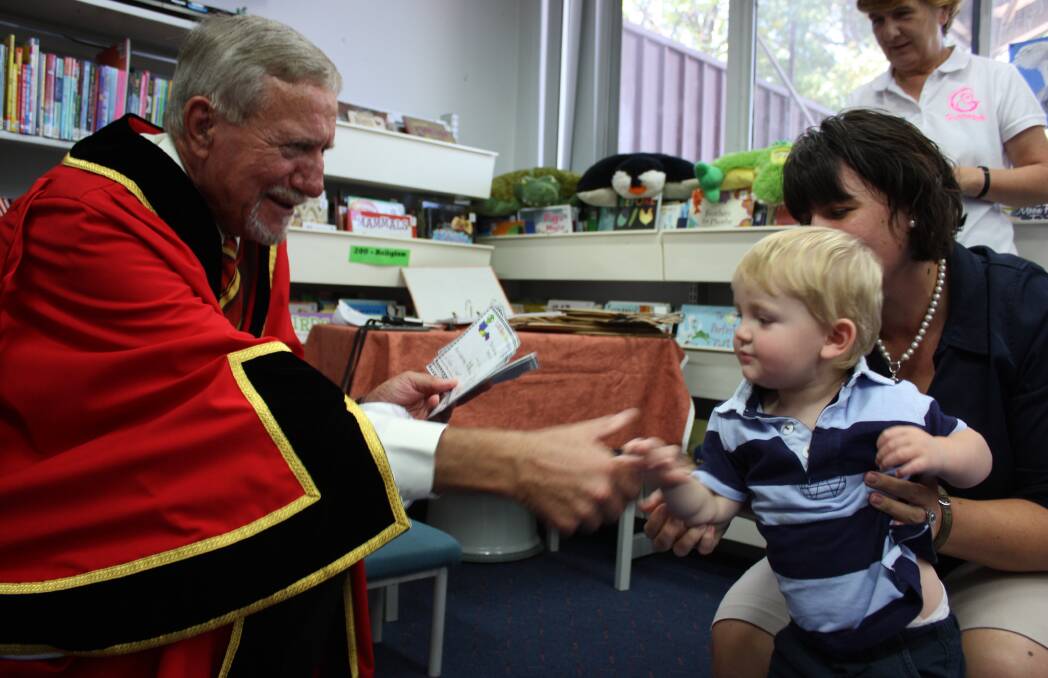 Gunnedah mayor Owen Hasler shakes Jake Grace’s hand and awards him with a certificate for reading 100 books.