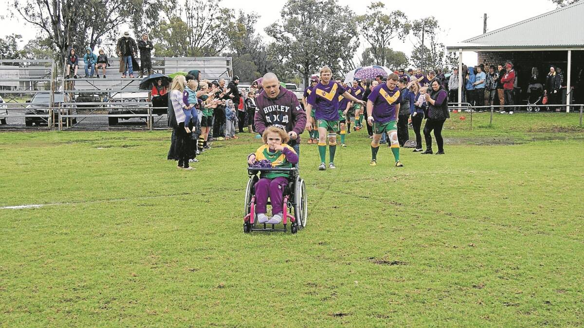 Jayda’s dad Craig wheels her onto the field as the Boggabri Kangaroos run out before the game. 