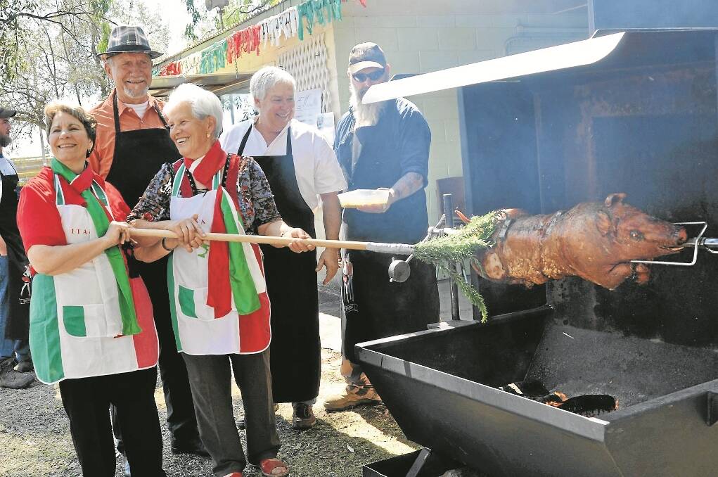 PROUDLY celebrating their Italian heritage, Jan and Maria Capezio basting the porchetta with rosemary dipped in olive oil, watched by Gunnedah Mayor Owen Hasler, Porchetta Day committee chair, Richard Gallen, and Jeff Redgrove.