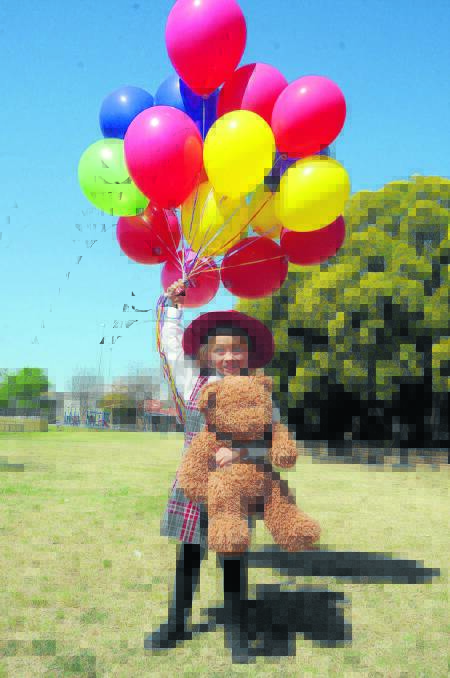 Gunnedah South pupil, Indiella Bryers (5) prepares for lift-off with her bunch of balloons and her teddybear at the Teddy Bear’s Picnic.