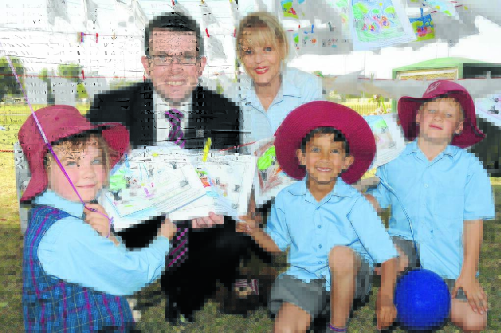 Gunnedah Mayor Adam Marshall and Robyn Gallen from Gunnedah Family Support looking at colouring-in entries made by students, pictured with St Xavier’s Class 1S pupils, from left, Mikayla Flew (6), Nayte Vernon (6) and Jim Brady (6).