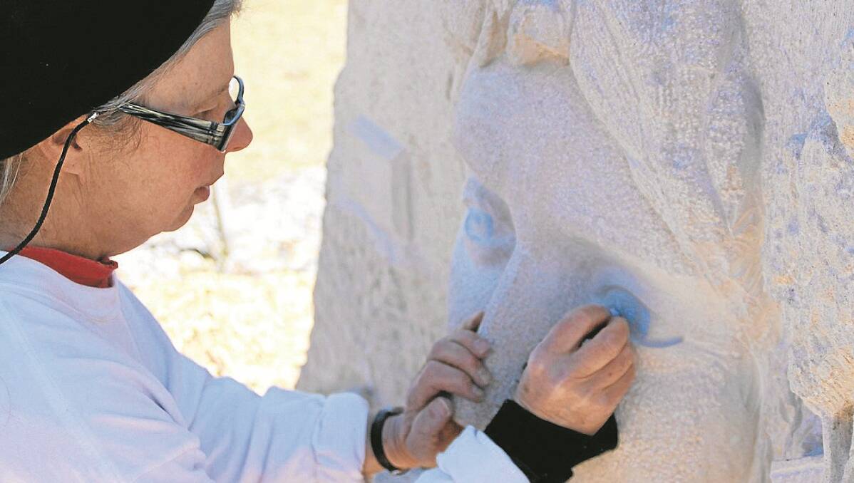 Lead sculptor Joan Relke places the all important eyes on the Pioneering Woman sculpture.